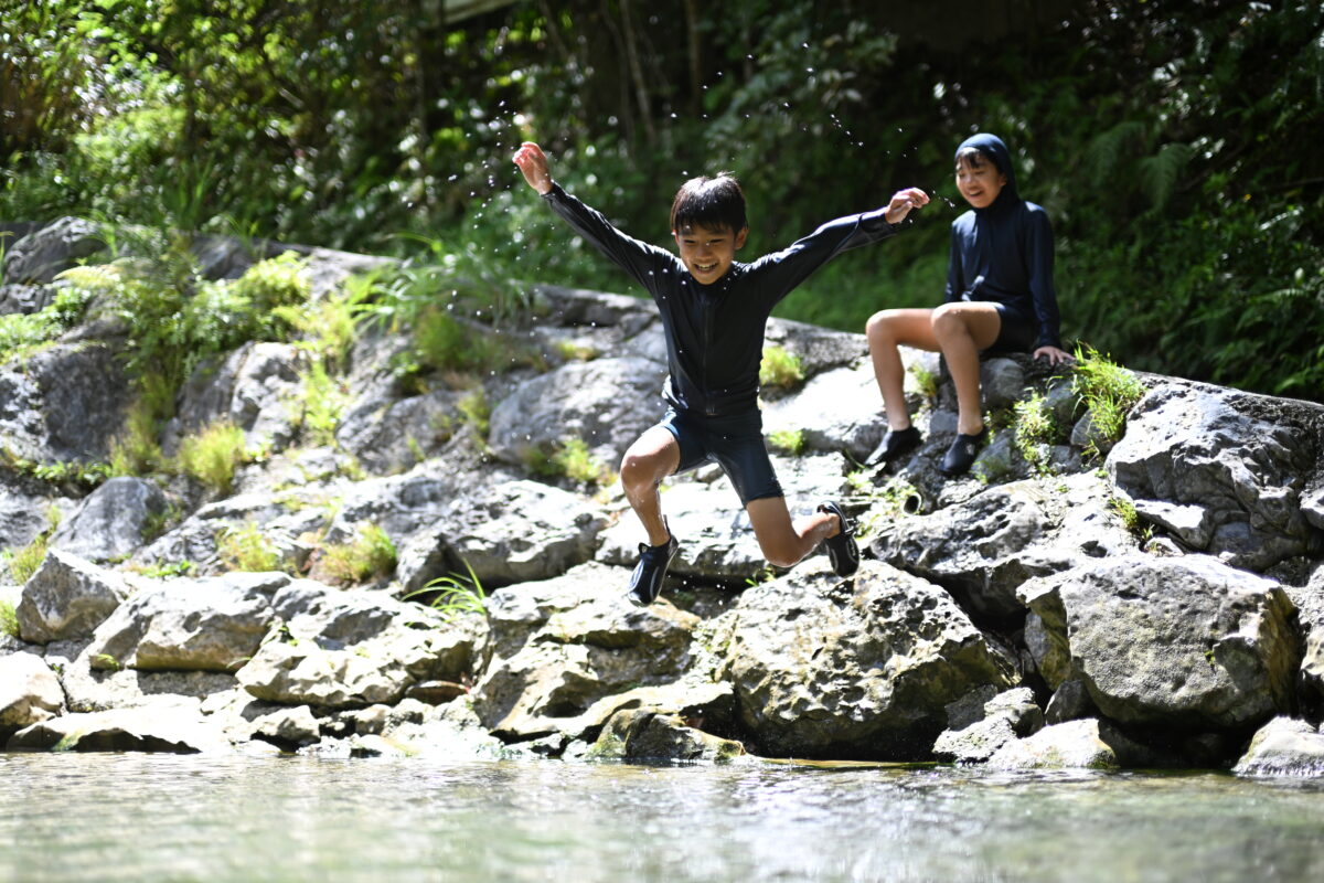 男の子が川へジャンプしている瞬間の写真