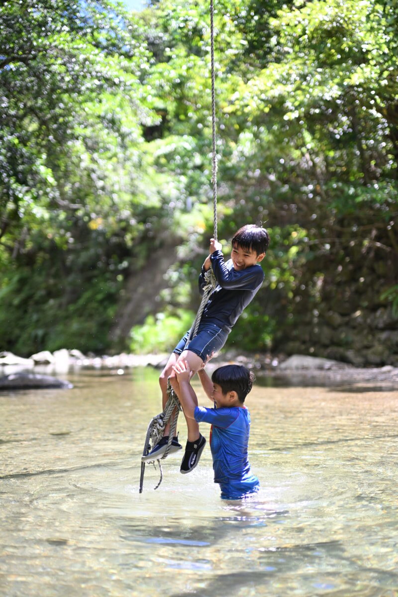 兄弟が川にあるロープで遊んでいる写真